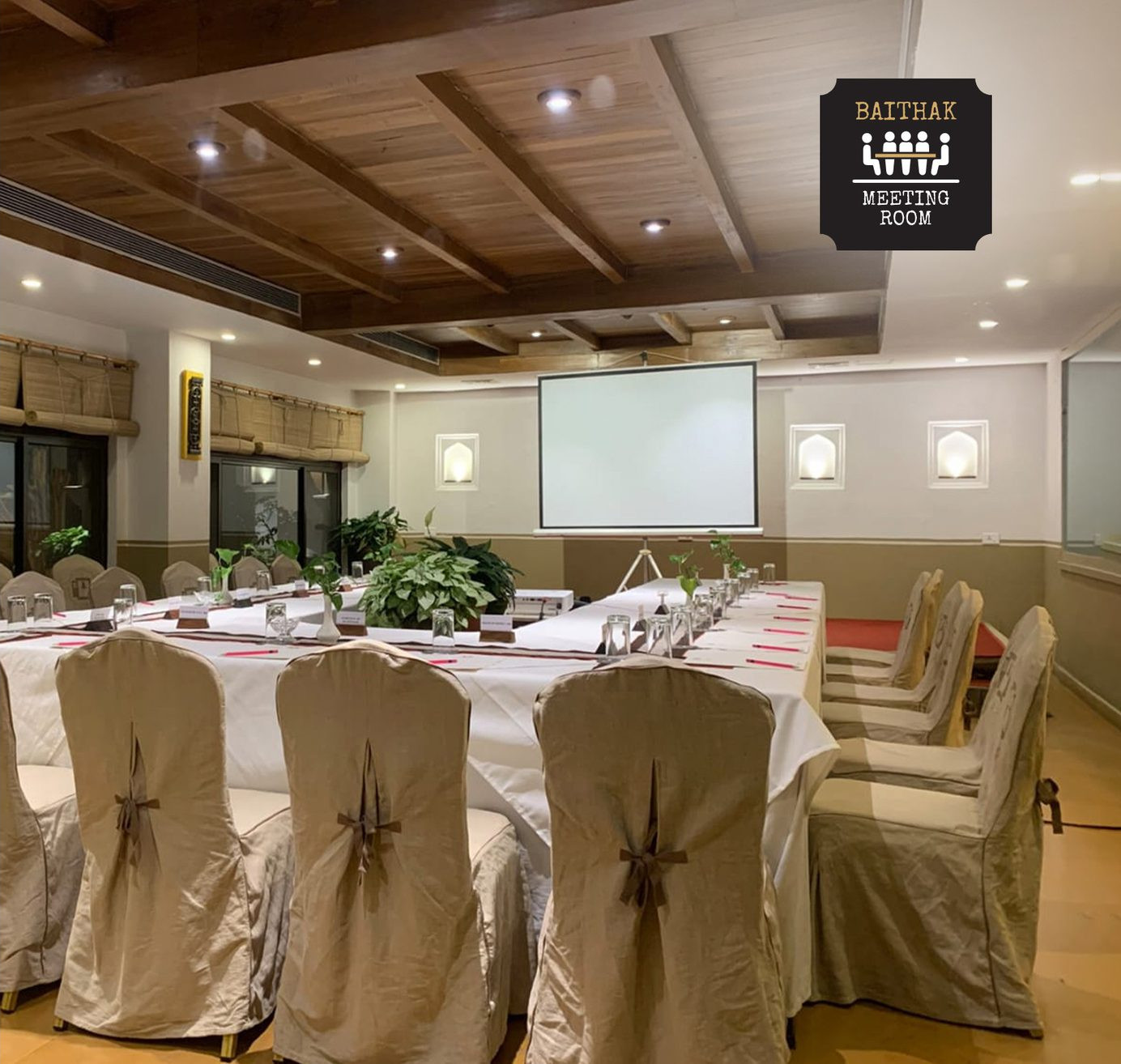 The Baithak meeting room set theatre-style with draped chairs and a projector screen