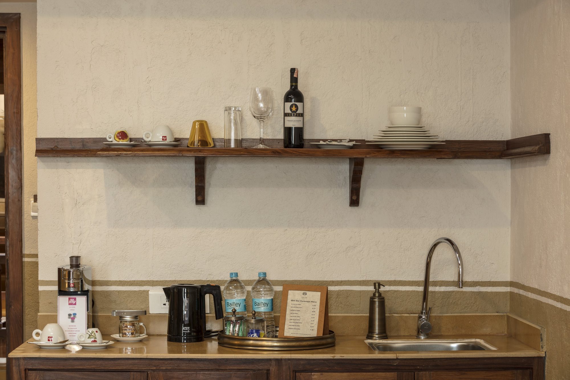 The Executive Suite pantry with an illy coffee machine, kettle, minibar, and a shelf of glassware