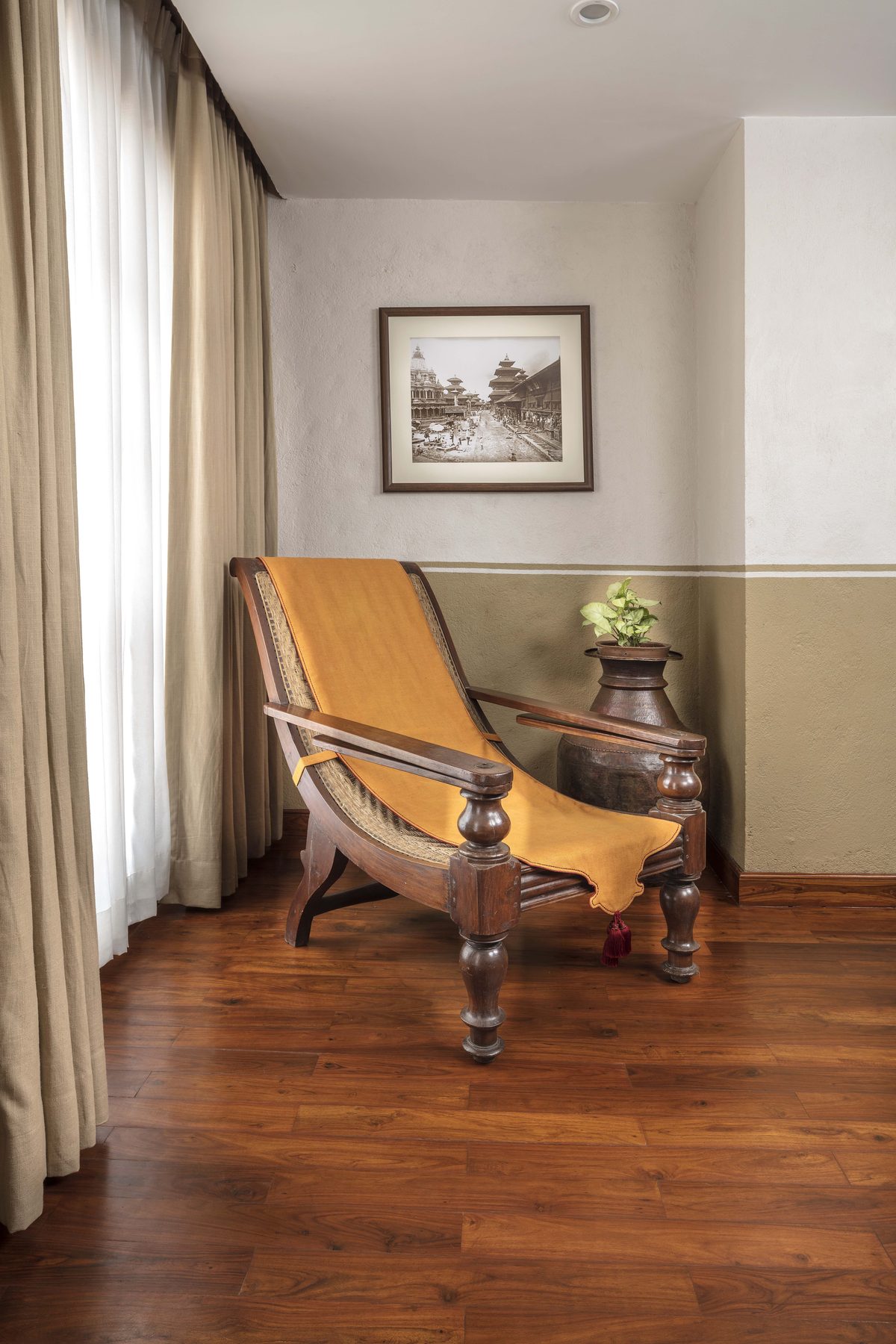 A caned planter&rsquo;s chair by the window of the Executive Suite, beside an archival photograph of Kathmandu