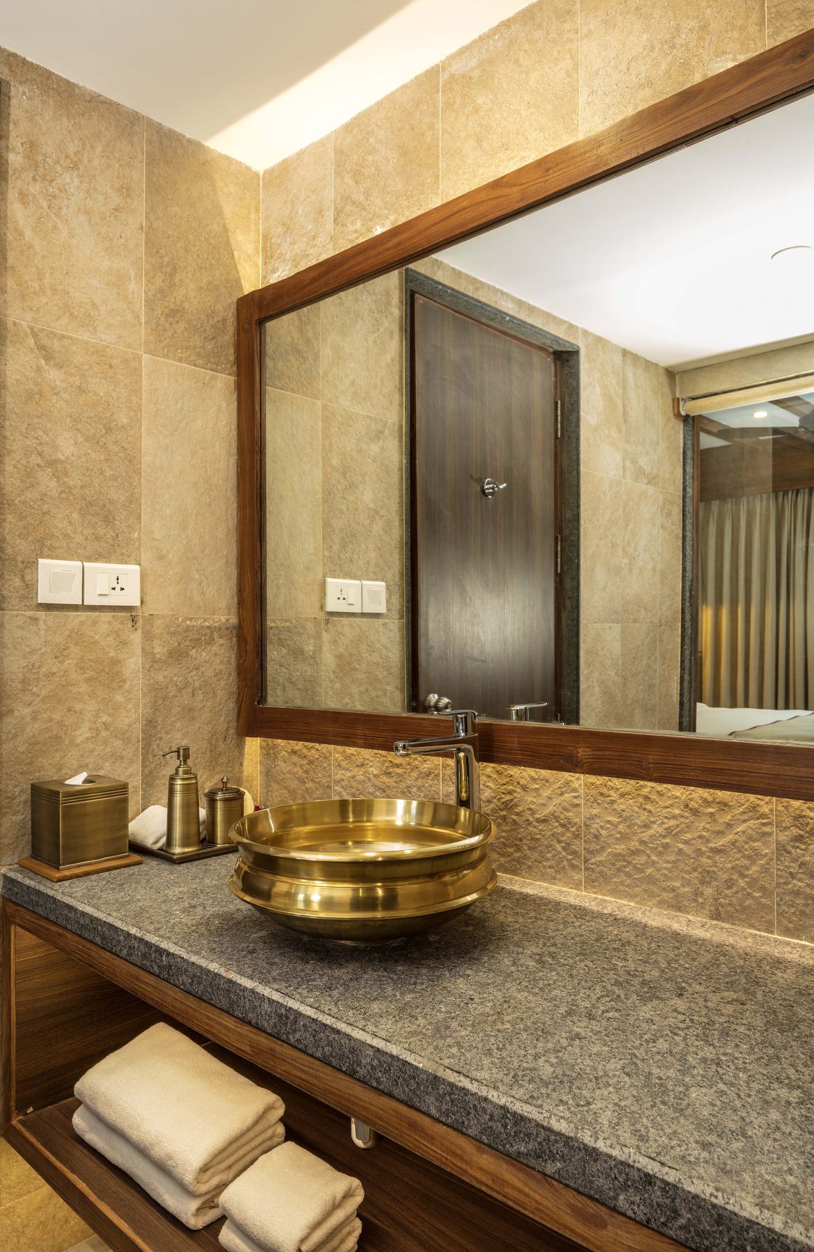 The Executive Suite bathroom vanity, a hammered brass basin on a stone counter beneath a timber-framed mirror