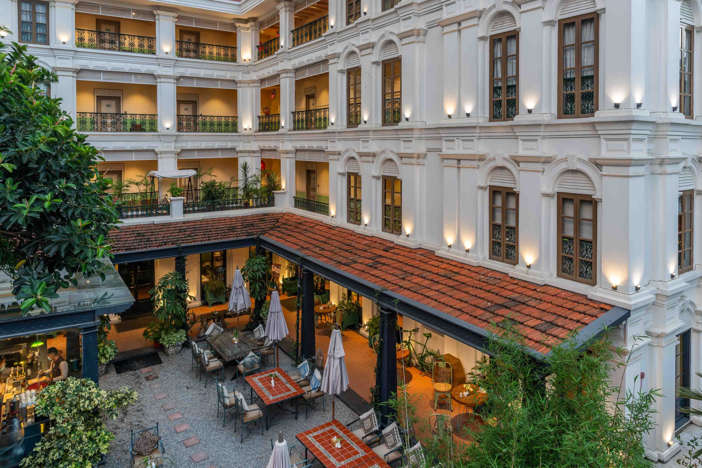 The Seto Ghar courtyard at dusk, ringed by tiered balconies above a tiled colonnade set with caf&eacute; tables