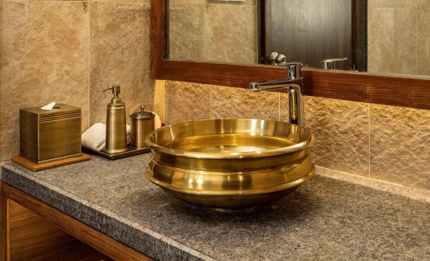 A brass basin beside refillable clay-pot bathroom amenities at Nepali Ghar