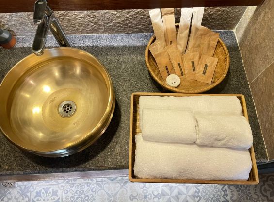 Rolled towels and a brass basin, part of the towel-and-linen reuse programme at Nepali Ghar